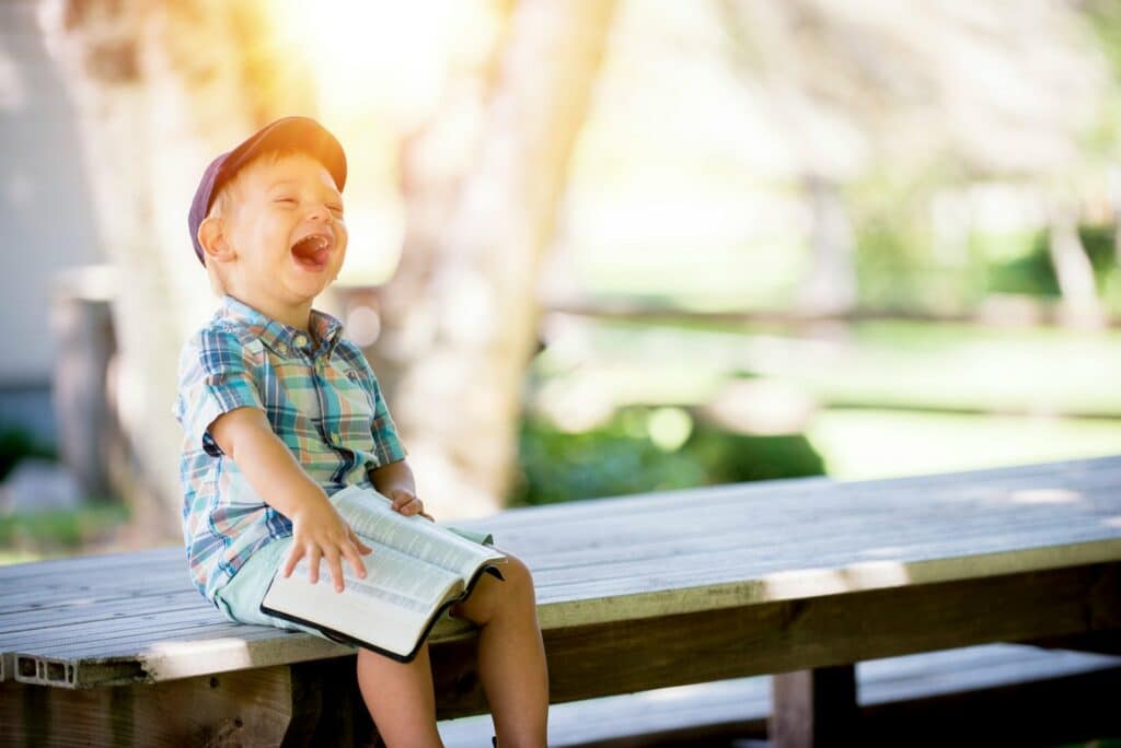 Young boy holding a book and laughing