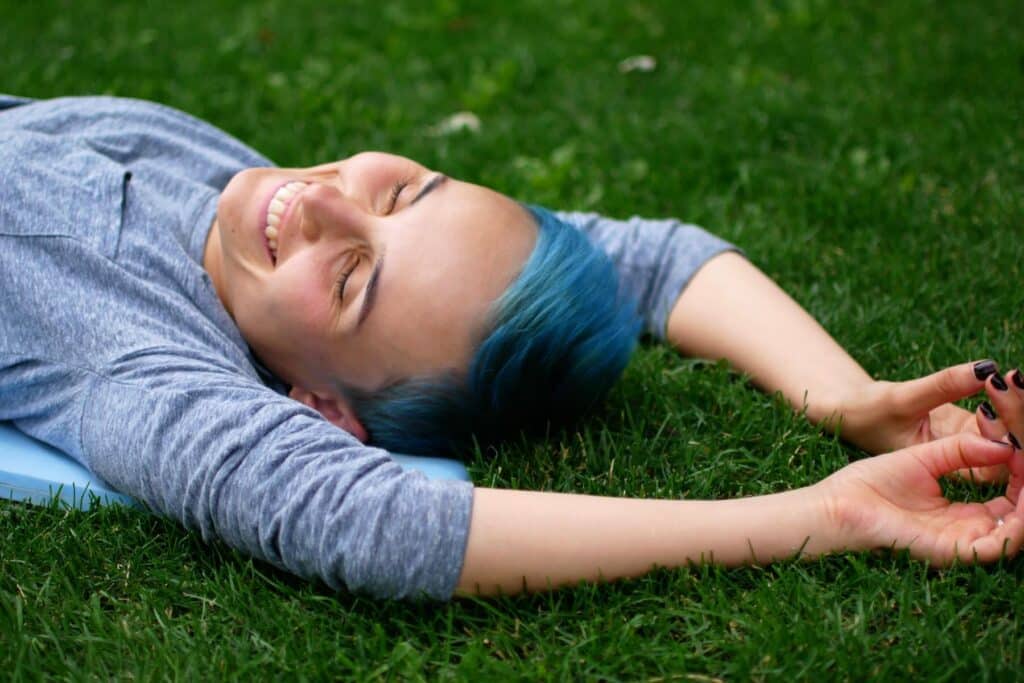cheerful woman lying down on the grass and laughing.