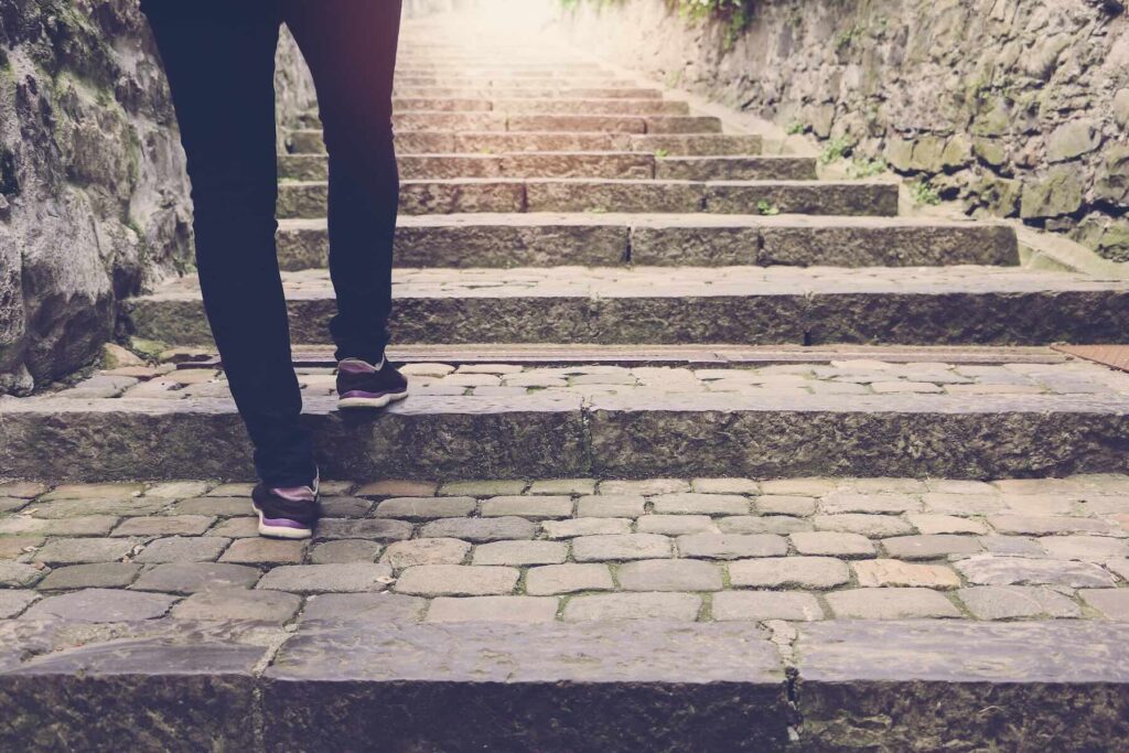 Woman walking up some outdoor stone stairs, background with vintage filter.