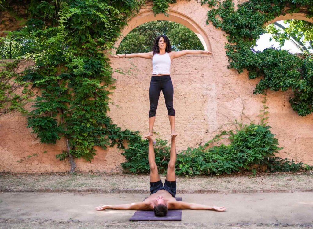 Beautiful man and woman doing acroyoga in the garden or park. Harmony and relaxation