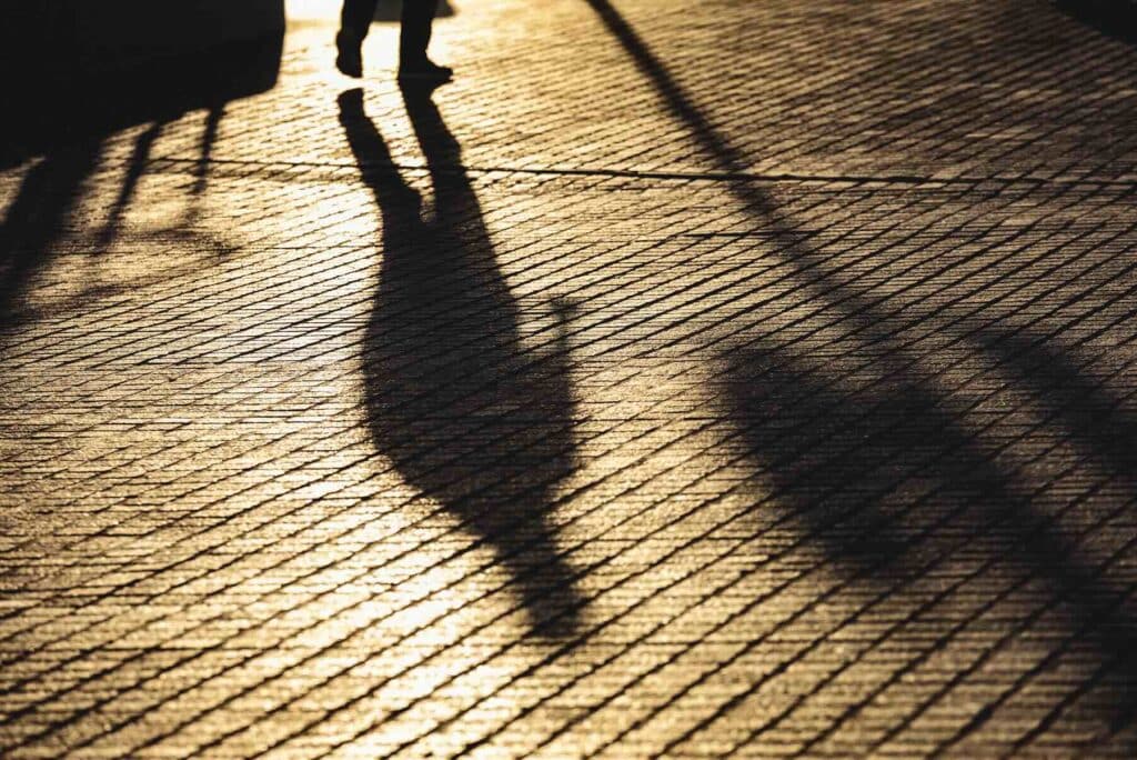 Abstract urban background with diffuse shadow of man walking at sunset, loneliness concept.